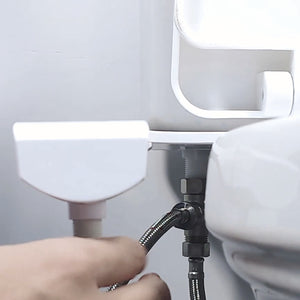 Une main raccorde le flexible en inox tressé à l’adaptateur en T sous le réservoir